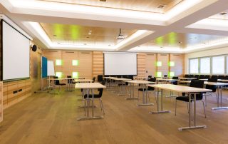 Modern classroom featuring rows of tables and chairs, a projector screen, and green accent lighting on wooden walls. Top School Floor Sanding Services in Birmingham